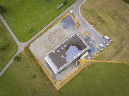 Aerial view of a construction site area with vehicles and a crane next to a partially completed