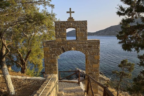Legend, crab, shell fisherman, stone arch with cross in front of a coastal view of the sea and