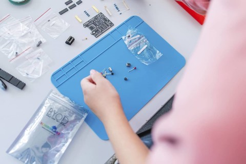 Person arranges electronic components on a blue pad with circuit board