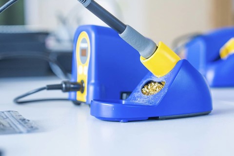 Blue soldering iron on a table with yellow accents and digital display