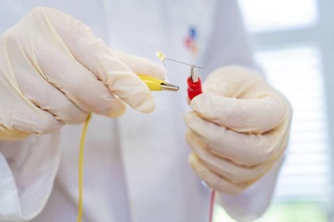 Researcher holds cable and LED in an electrical experiment in the laboratory, Battery Research,