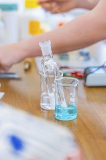 Chemistry experiment with blue liquid beaker on wooden table, Battery Research, Nagold, Germany