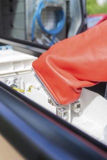 Red glove focusses on safe work with electrical connections, assembly of a charging station for
