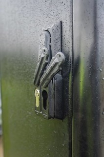 Wet lock on a black door with visible water droplets and reflected light, installation of a