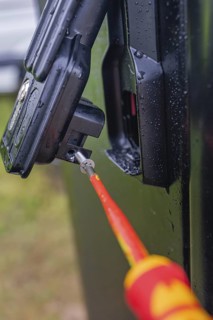Close-up of a screwdriver attached to a black housing, covered with water droplets, assembly of a