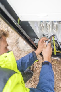 Worker fixing cables with tools in an electrical installation, assembly of a charging station for