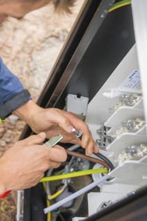 Person installing electrical cables in a switch box with tools, installing a charging station for