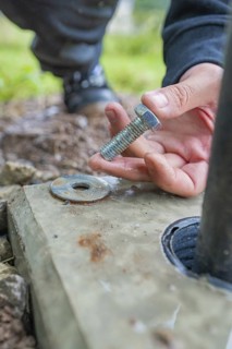 Hand holding a screw for mounting on a concrete base, installation of a charging station for
