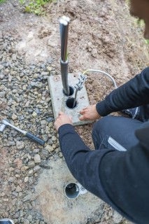 Worker attaching electrical cables to a grounding device on the ground, assembly of a charging