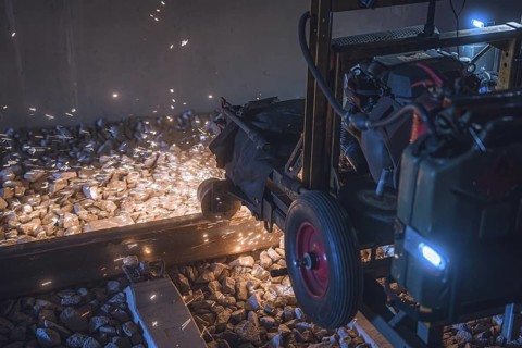 A machine that sprays sparks and works on ballast between rails. A dynamic and industrial feeling