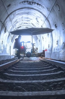 Machine used in the tunnel with umbrella-like construction on rails, surrounded by light and