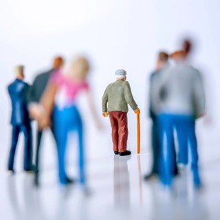 A group of diverse individuals stands behind an elderly man with a cane, who is walking forward,