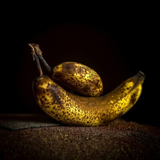 Two ripe bananas, one larger and one smaller, showcase their dark speckled skins. Positioned on a