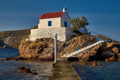 A small church with a red roof lies on a rock, accessible via steps and a pier, chapel, church,