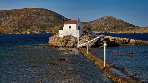 Chapel on an island, framed by blue sky and mountains, with access via a footbridge, Chapel,