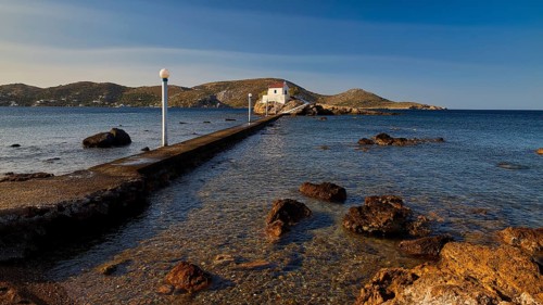 A stone pier leads to a church standing on a rock in the calm sea, chapel, church, Agios Isidoros,