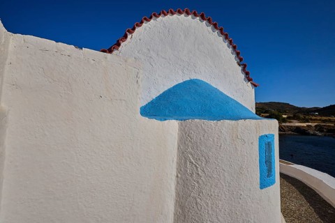 Close-up of a white church wall with blue accents and red roof, chapel, church, Agios Isidoros,