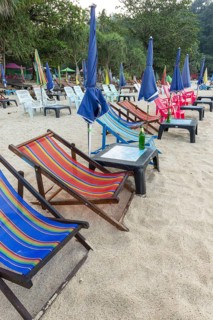 Abandoned deckchairs and parasol after sunset at Charlie Beach, Koh Mook Island, Andaman Sea,