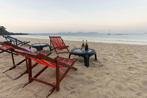 Abandoned deckchairs and parasol after sunset at Charlie Beach, Koh Mook Island, Andaman Sea,