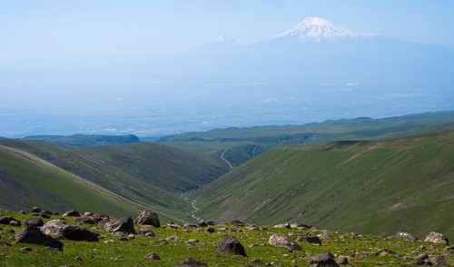 Extensive landscape with green valleys and snow-capped mountains on the horizon, view from Aragaz