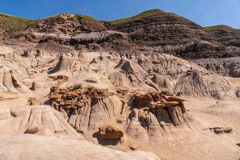 Sunlight illuminates the otherworldly landscape of the drumheller hoodoos, showcasing unique