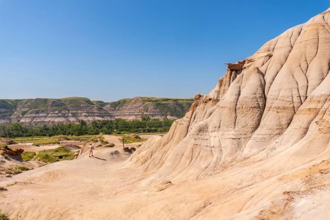 Tourist walking through the arid badlands of drumheller, alberta, surrounded by unique hoodoo
