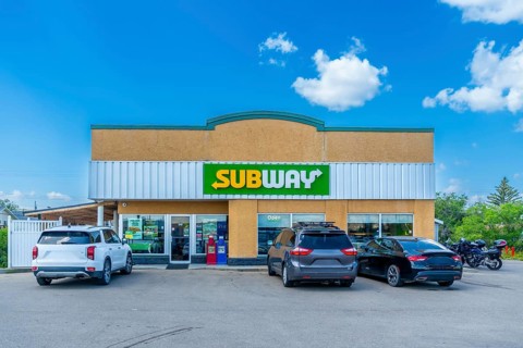 Sandwich restaurant chain with parking lot and cars parked in front on a sunny day with blue sky