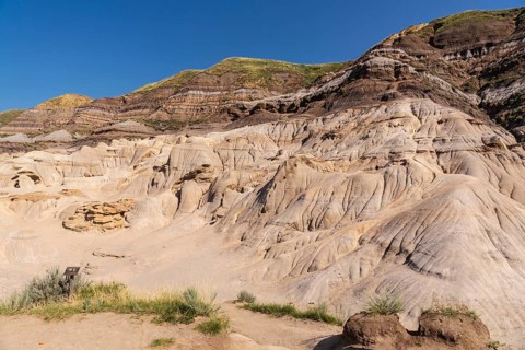 Sunlight bathes the otherworldly terrain of drumheller, alberta, showcasing the unique hoodoo