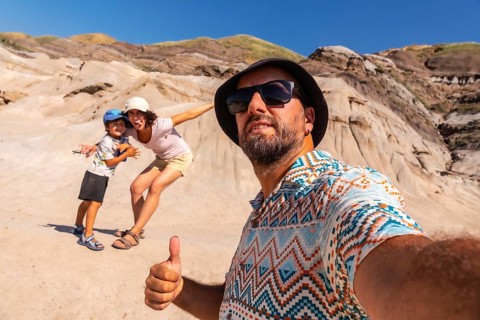 Family taking a selfie with thumbs up gesture in front of the unique hoodoos landscape of