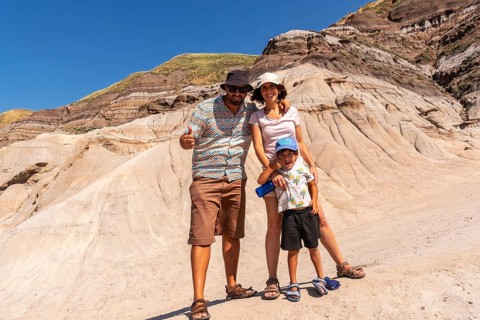 Happy family of tourists standing in front of the unique geological formations of drumheller,