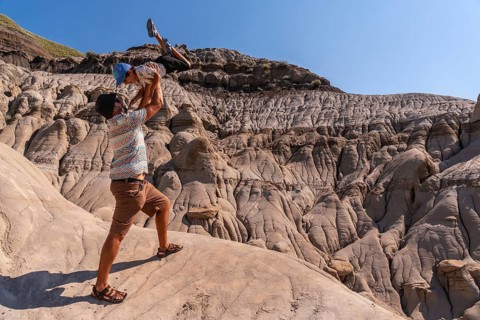 Father playfully lifting his son in the air at horseshoe canyon in drumheller, alberta, canada,