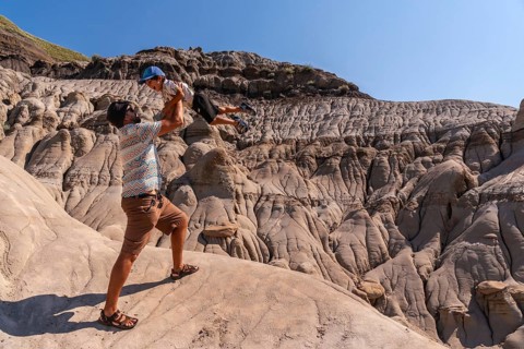 Tourist father lifting his son in the air, having fun in front of the unique geological formations