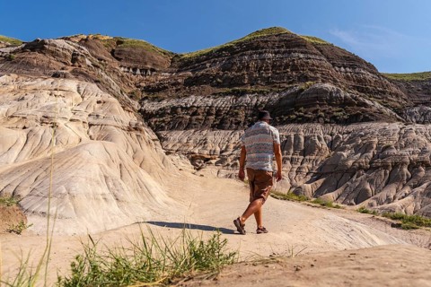 Tourist exploring the arid landscape of the canadian badlands, walking through the unique
