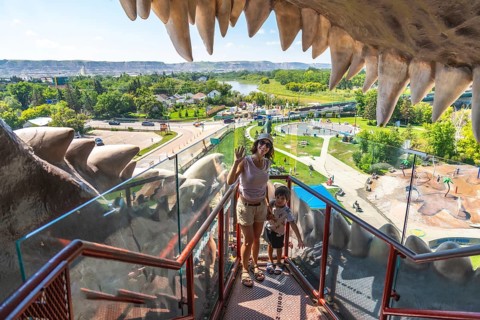 Tourists waving from the mouth of the world's largest dinosaur statue, taking in panoramic views of