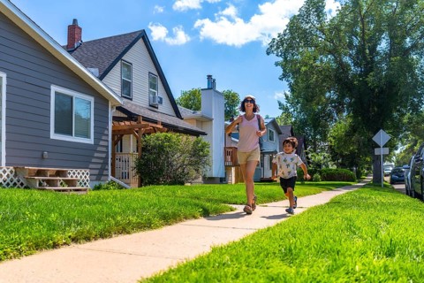 Mother and her young son are running on the sidewalk in a quiet, residential neighborhood on a
