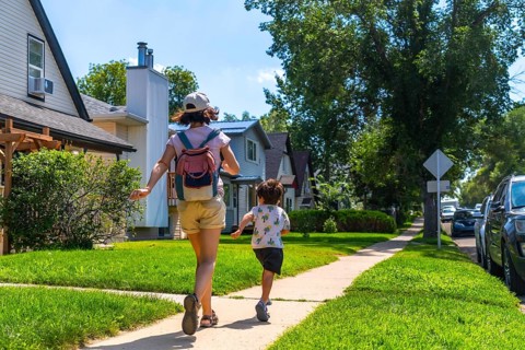 Mother and son running joyfully on the sidewalk in a residential neighborhood of drumheller,