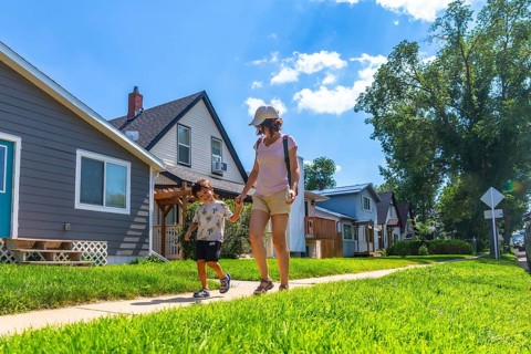 Mother and son walking hand in hand on a sunny day along a sidewalk in a peaceful drumheller