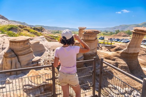 Young woman enjoying view of unique hoodoo rock formations at tourist attraction in drumheller,