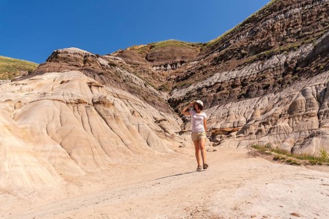 Female tourist walking through the arid and eroded landscape of drumheller valley in the canadian
