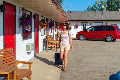 Female tourist pulling her luggage while strolling towards her room at a roadside motel, enjoying a