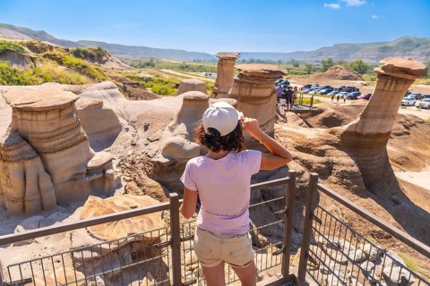 Young woman shielding her eyes from the sun while admiring unique hoodoo rock formations in