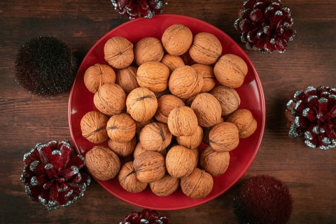 Red plate with walnuts surrounded by sparkling cones