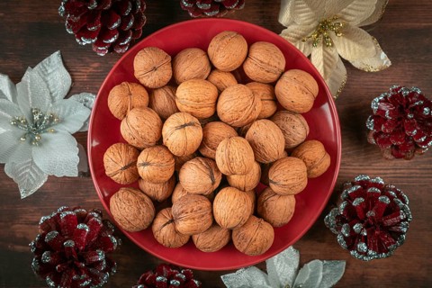 Walnuts on red plate surrounded by festive Christmas decorations