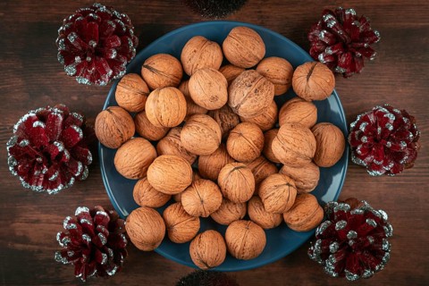 Blue plate full of walnuts surrounded by decorative cones