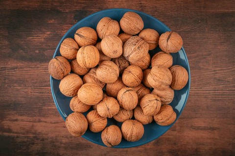 Blue plate with walnuts in the center of a wooden table