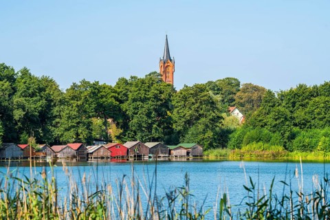 View across the Haussee to the town church and colorful boathouses on stilts, Feldberg, Feldberg