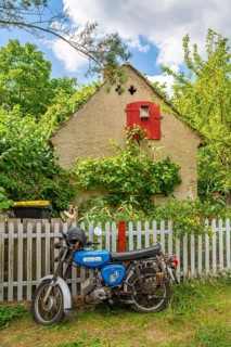 Blue motorcycle from the GDR brand Simson stands in front of an old house, village of Carwitz,