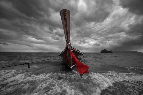 Longtail boat on the beach with dark rain clouds behind it, Koh Ngai island, Andaman Sea, Satun