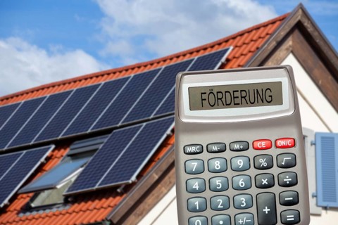 (photo montage) Pocket calculator with the inscription PROMOTION in front of a solar roof