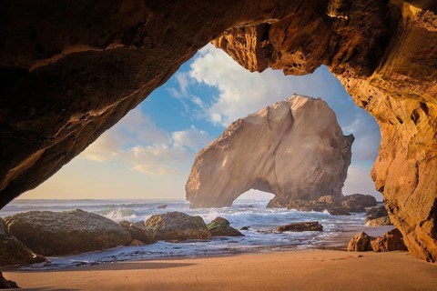 Penedo do Guincho, a large boulder rock arch at Praia da Santa Cruz, Portugal, with ocean waves and